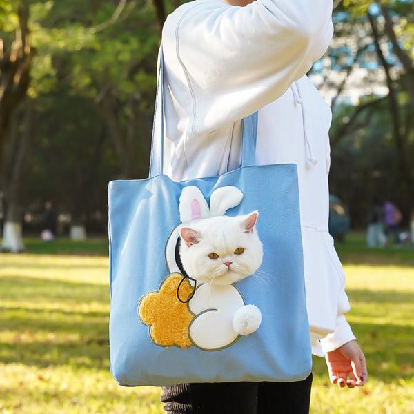 Person holding a tote bag with a cat design in a park