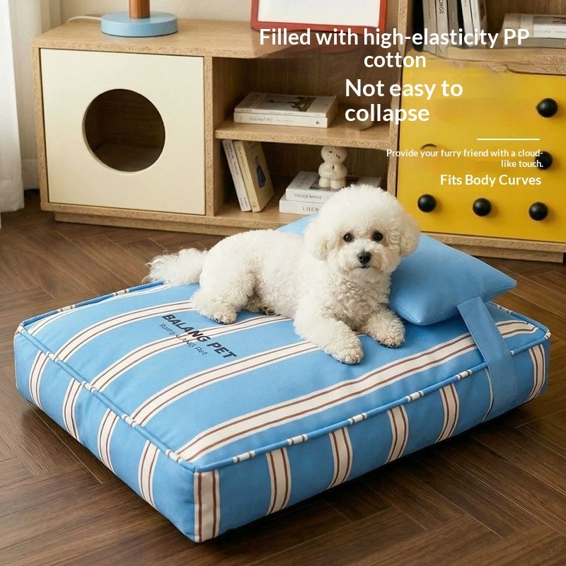 A small white dog lies on a rectangular pet bed with a blue pillow in a home interior. The bed is light blue with white and brown stripes and the words 'BULLING PET' printed on the front.