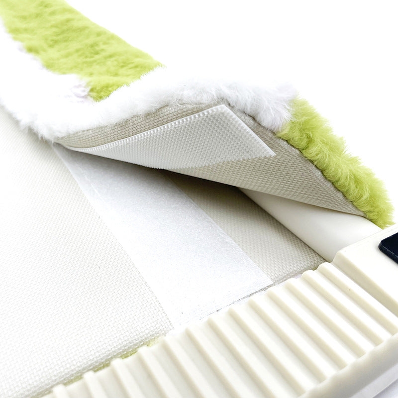 Close-up of a green and white cleaning brush with a textured handle.