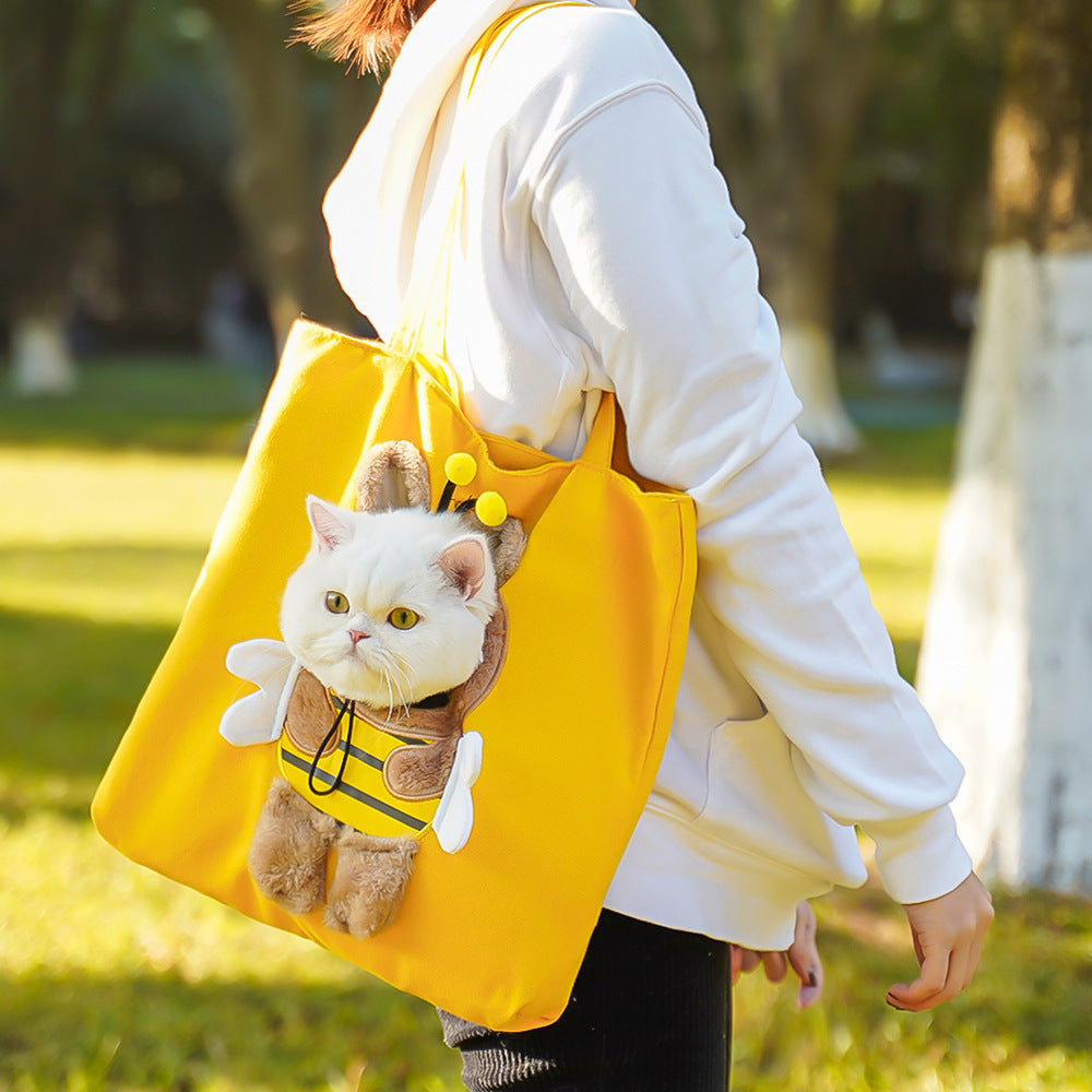 Person holding a yellow tote bag with a cat plushie in an outdoor setting