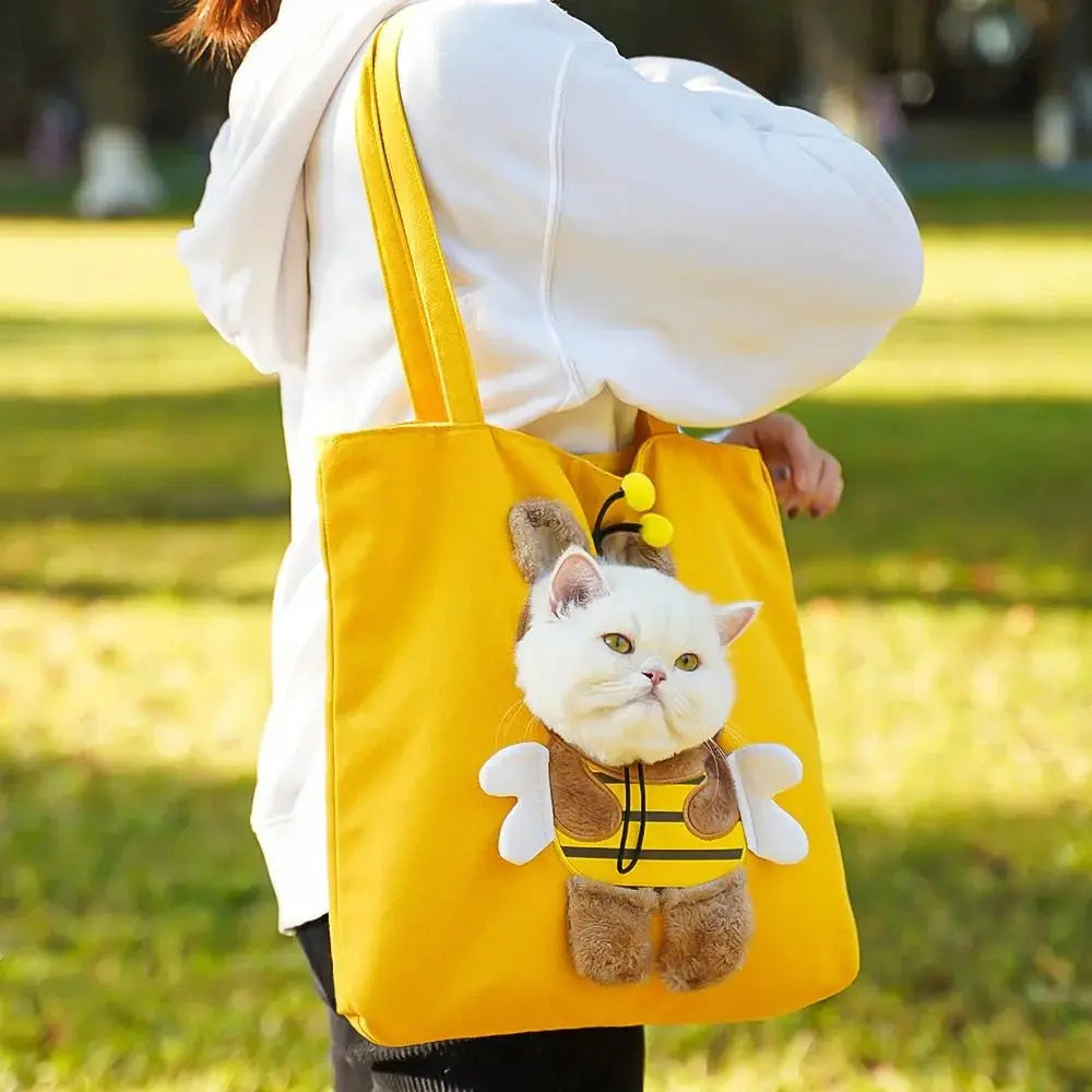 Yellow tote bag with a cat plushie attached, held by a person outdoors.