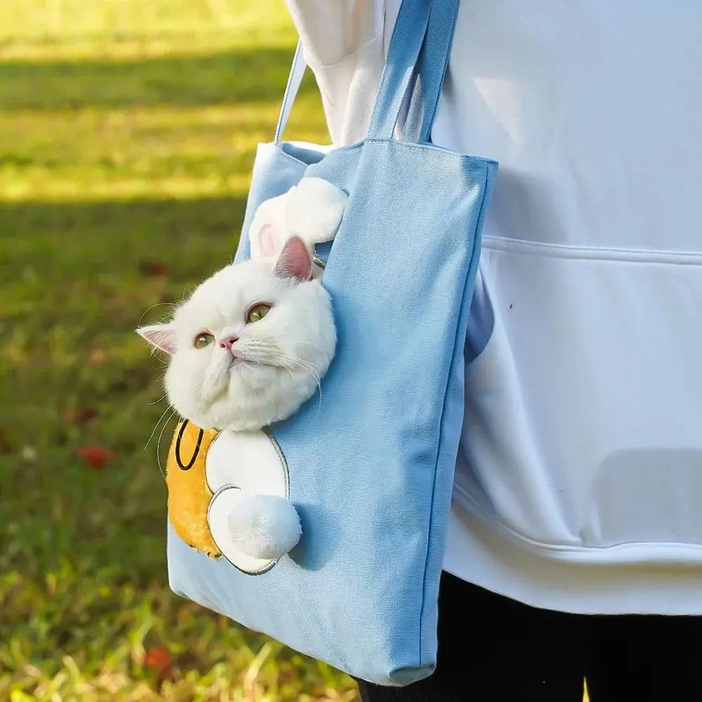 Person holding a blue tote bag with a cat design outdoors