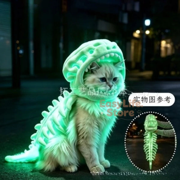 A fluffy cat wearing a glowing green dinosaur costume in a dark outdoor nighttime setting, with a circular inset showing the costume's skeleton detail.