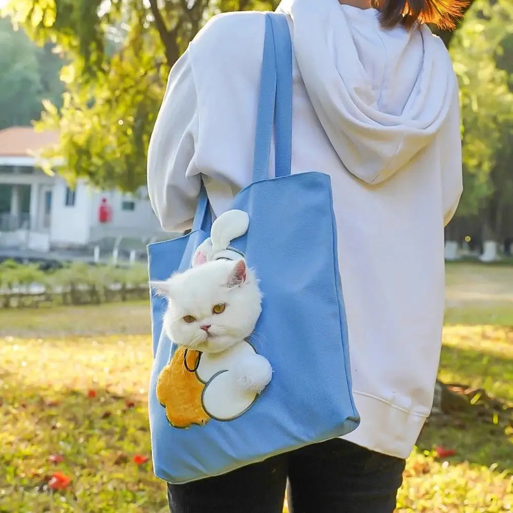 Person holding a blue tote bag with a cat design outdoors