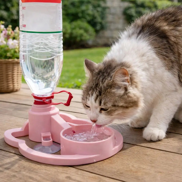 Cat drinking water from a pink pet water fountain outdoors.
