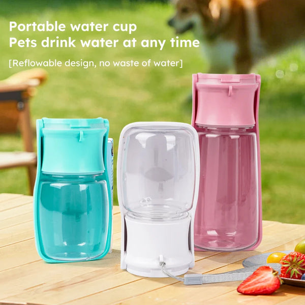 Three portable water cups in blue, clear, and pink on a wooden table with a grassy background.