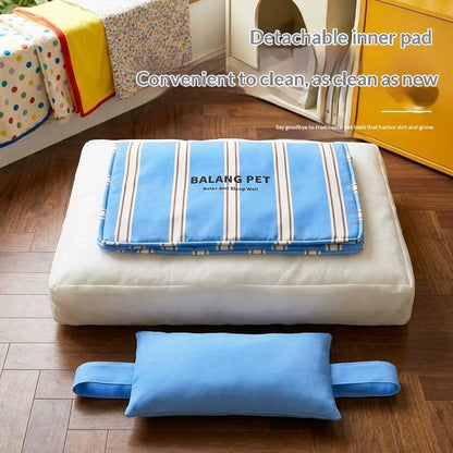 A pet cushion set shown on a wooden floor in a room, featuring a white rectangular cushion with a blue striped detachable inner pad labeled 'BALANG PET' and a separate blue rectangular support pad placed in front. Text on the image describes the detachable inner pad and cleaning convenience.